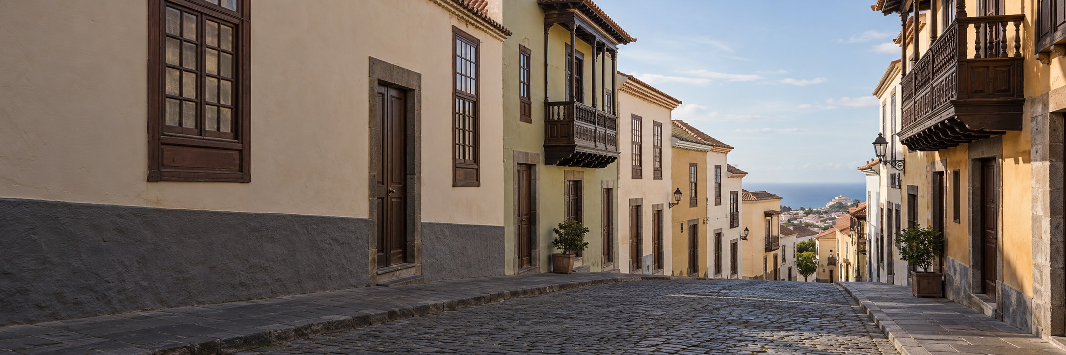 Calle empedrada con balcones canarios de madera y el mar al fondo